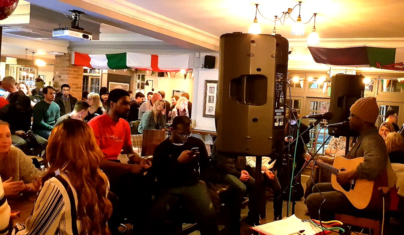 Customers enjoying a live cover artist in a busy pub